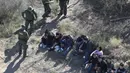 Petugas menangkap imigran Meksiko yang berusaha menyeberangi perbatasan AS-Meksiko di McAllen, Texas (3/1). Ribuan imigran masuk secara ilegal melintasi perbatasan mencari suaka di AS jelang pelantikan AS Donald Trump. (AFP Photo/John Moore/Getty Images)