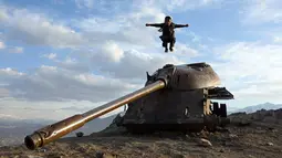 Seorang anak melompat di atas bangkai tank Soviet di puncak bukit di pinggiran Kabul, Afghanistan (4/3). Karena Afghanistan negara yang dilanda konflik, banyak barang-barang sisa perang yang dibiarkan begitu saja. (AP Photo/Rahmat Gul)