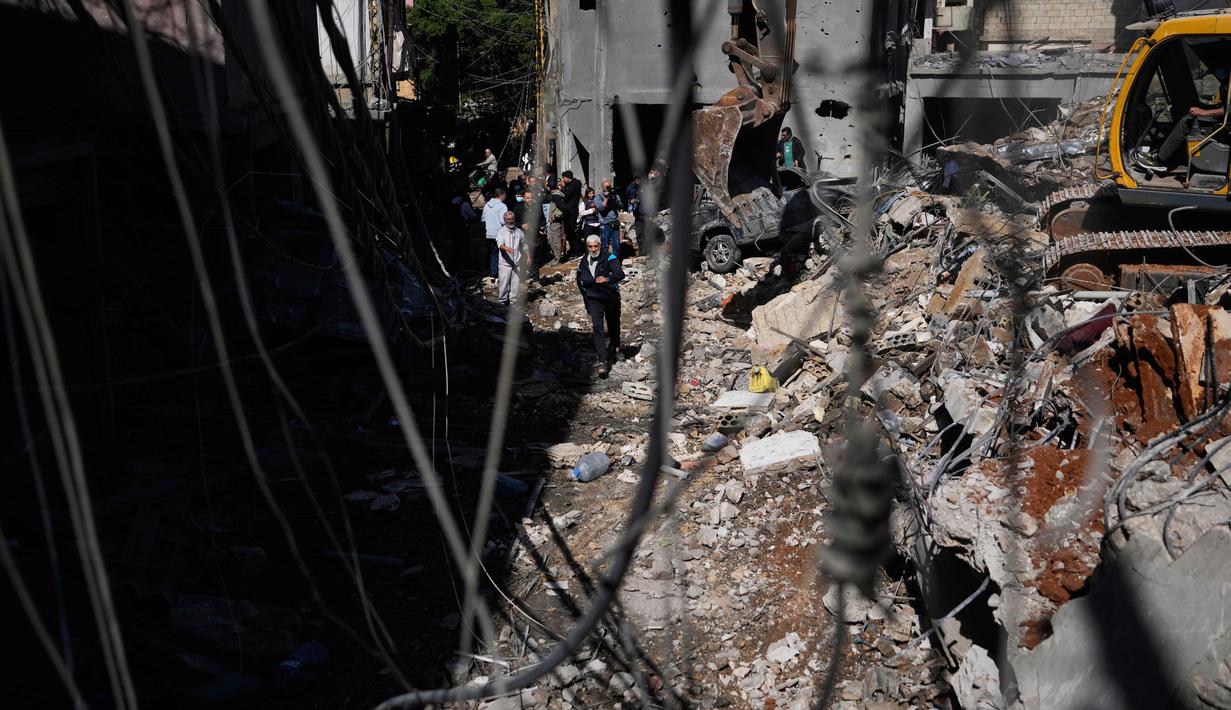 Dua jembatan di Sungai Litani yang menghubungkan wilayah Sohmor dan Machghara di Bekaa Barat, Lebanon, dilaporkan hancur dihantam serangan udara Israel. Tampak dalam foto, orang-orang berkumpul saat sebuah ekskavator membersihkan puing-puing di lokasi serangan Israel pada Minggu 5 April 2026 terhadap sebuah bangunan di lingkungan Jnah, Beirut, Lebanon, Senin 6 April 2026. (AP Photo/Hassan Ammar)