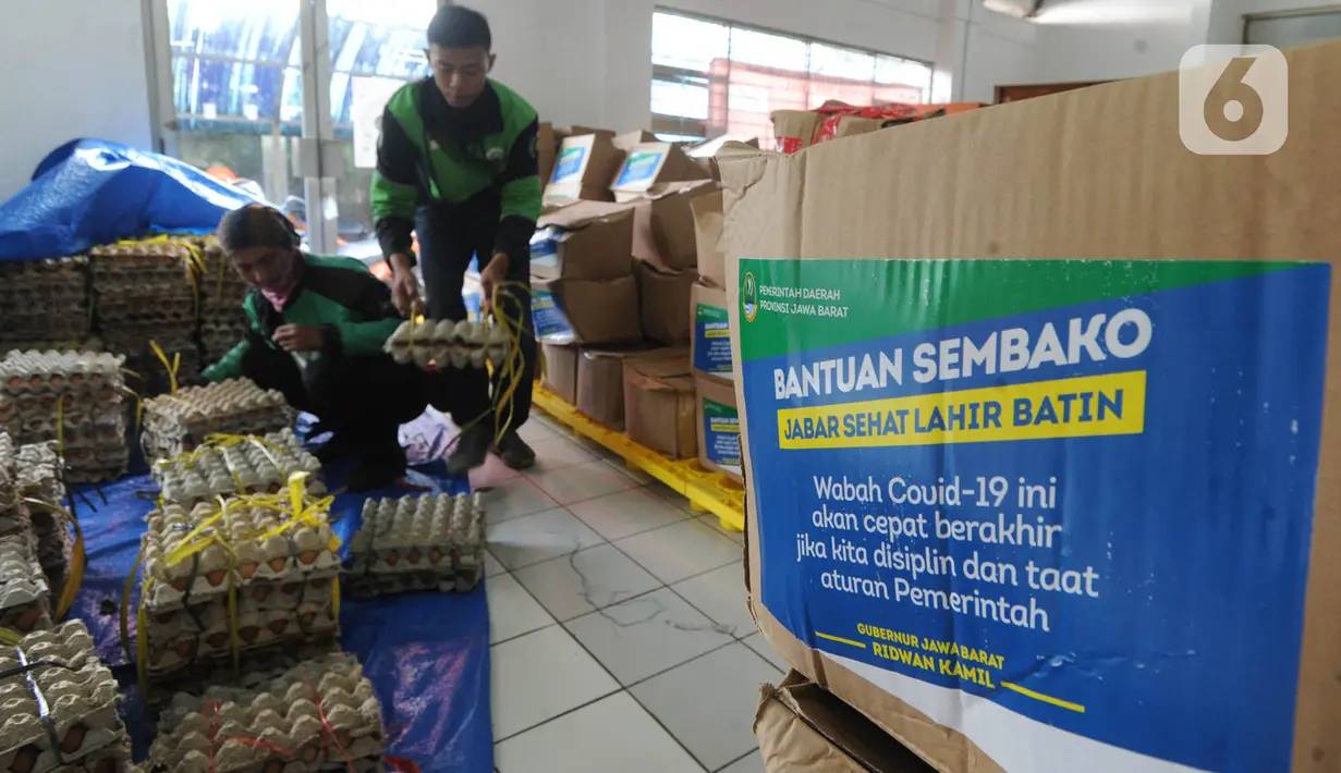 Pengemudi ojek online mengemas bansos untuk warga yang terdampak COVID-19 di Kantor Pos, Cibinong, Bogor, Jawa Barat, Senin (20/4/2020). Bansos khususnya disalurkan di zona merah persebaran yaitu Bogor, Depok, dan Bekasi dengan memberdayakan ojek online. (merdeka.com/Arie Basuki)