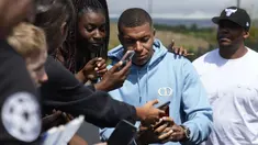 Penyerang Paris Saint-Germain (PSG), Kylian Mbappe berswafoto dengan fans saat meninggalkan kompleks latihan Paris Saint-Germain, di Poissy, di luar Paris, Jumat (28/7/2023). Spekulasi memuncak tentang di mana Mbappe akan memainkan pertandingan pertamanya musim ini. (AP Photo/Lewis Joly)