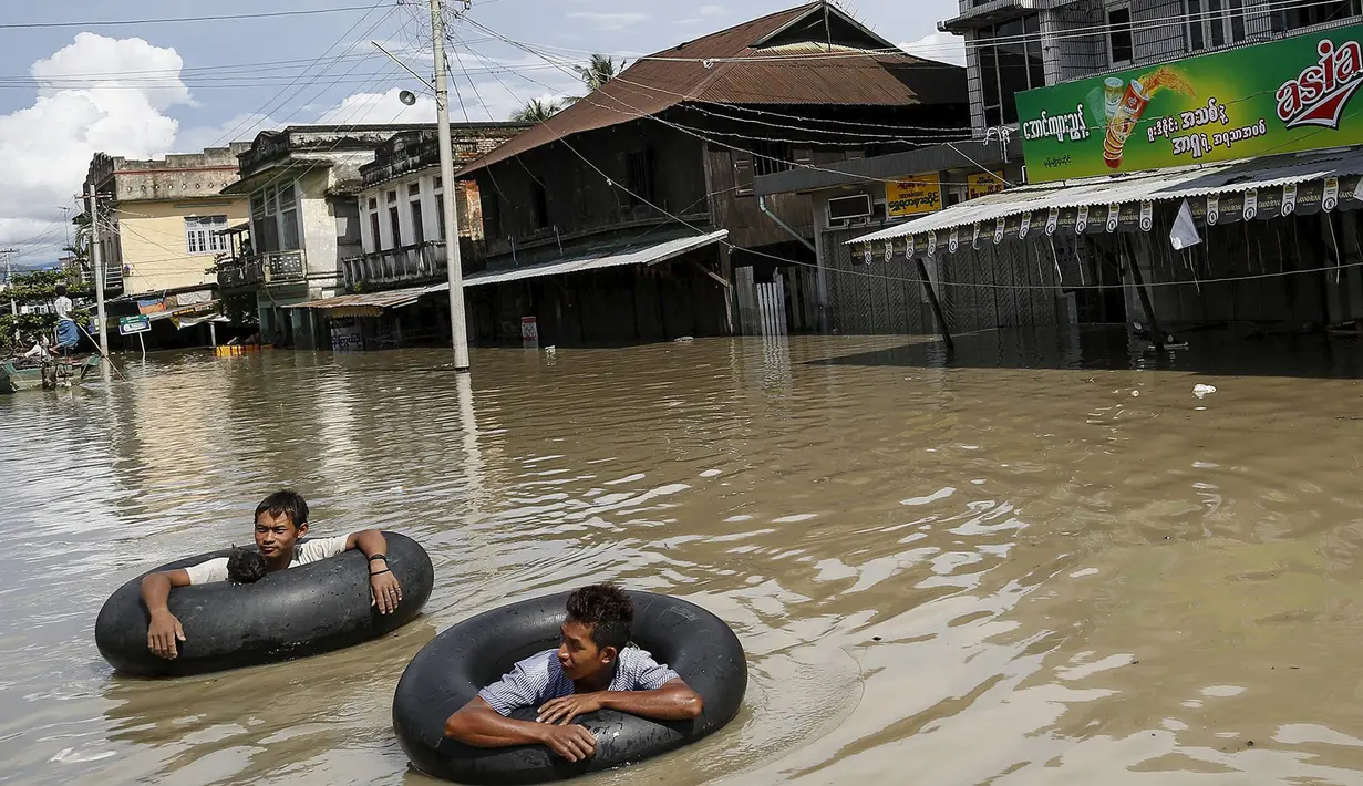 Warga menggunakan ban untuk melintasi jalanan yang terendam banjir di kawasan Kalay, Sagaing, Myanmar, Minggu (2/8/2015). Setidaknya 21 orang tewas akibat banjir yang melanda empat wilayah di Myanmar. (REUTERS/Soe Zeya Tun)