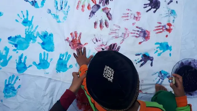 Aktivis membimbing anak-anak untuk mencetak cap tangan di lembar kain putih. (Foto: Liputan6.com/Muhamad Ridlo)