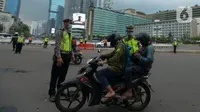 Polisi mengimbau pengguna jalan yang menggunakan kendaraan pribadi mobil dan motor yang berboncengan di Bundaran HI, Jakarta, Jumat (10/4/2020). Penerapan hari pertama PSBB hingga 14 hari kedepan ini dilakukan untuk mencegah penyebaran COVID-19 dan selalu menggunakan masker.(merdeka.com/Imam Buhori)