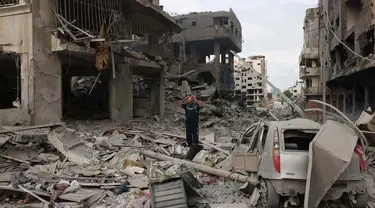 Seorang pria Palestina berjalan melewati puing-puing di tengah kehancuran akibat serangan udara Israel di lingkungan al-Rimal, Kota Gaza, pada 10 Oktober 2023. (MOHAMMED ABED/AFP)