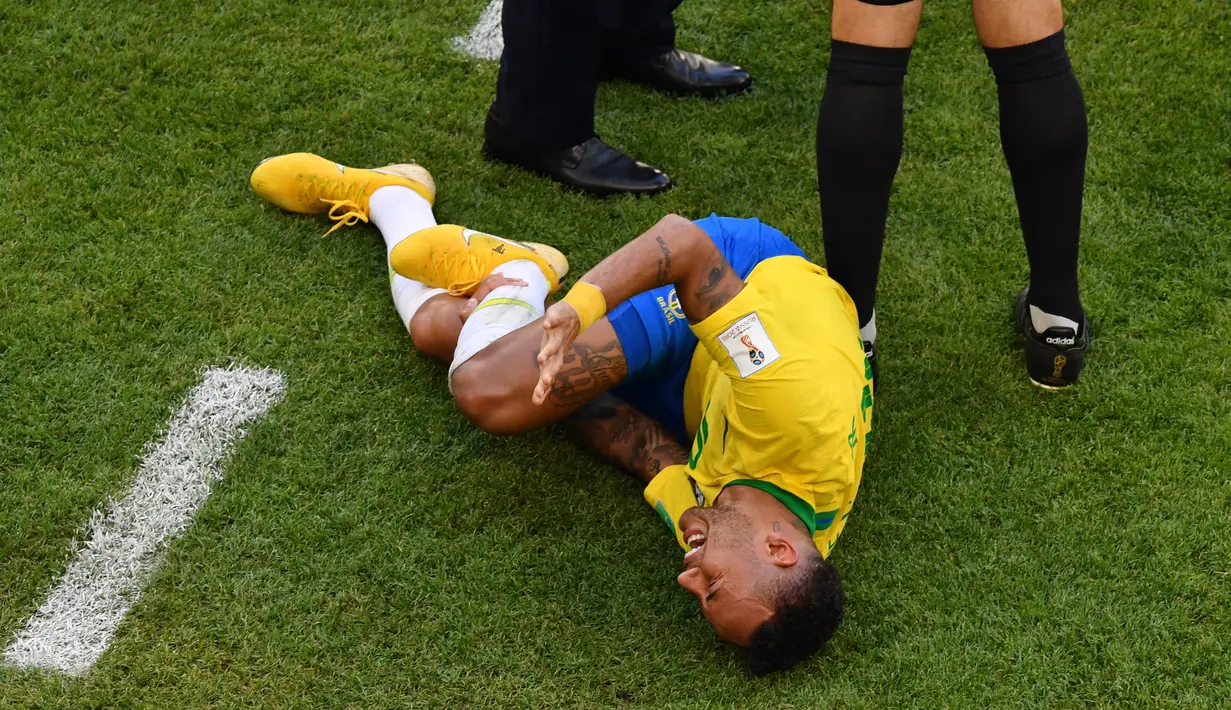 Penyerang timnas Brasil, Neymar mengerang kesakitan pada babak 16 besar Piala Dunia 2018 melawan Meksiko di Samara Arena, Senin (2/7). Jagat media sosial pun dibuat riuh oleh penggemar yang marah dan menyalahkan Neymar dengan sandiwaranya (AFP/SAEED KHAN)