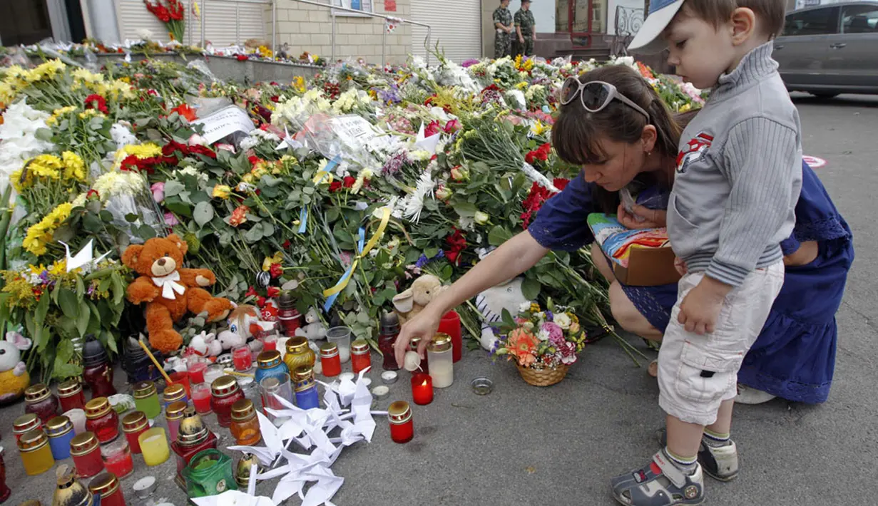 Penduduk setempat menyalakan lilin untuk para korban Malaysia Airlines MH-17 di luar kedutaan Belanda di Kiev, (19/7/2014). (REUTERS/Valentyn Ogirenko) 