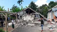 Penduduk desa berjalan di depan rumah yang roboh akibat gempa di desa Sajang, Sembalun, Lombok Timur, Minggu (29/7). Data sementara mencatat, gempa bumi tektonik 6.4 SR itu mengakibatkan 10 orang meninggal dunia dan puluhan rumah rusak. (AP/Rosidin)
