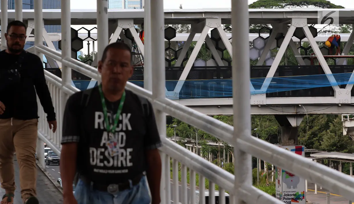 Pejalan kaki melintasi JPO di Dukuh Atas, Jakarta, Kamis (20/12). Pembangunan JPO Halte Transjakarta Dukuh Atas sisi Timur dilakukan untuk merelokasi JPO yang posisi tiang (kolom penyangga) berada di tengah ruas jalan. (Liputan6.com/JohanTallo)