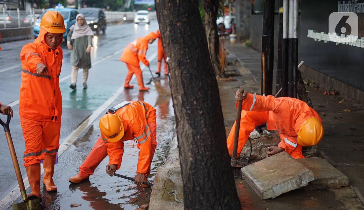 Petugas PPSU membersihkan saluran air yang tersumbat di Jalan Mampang Prapatan Raya, Jakarta, Rabu (11/12/2019). Hal tersebut dilakukan guna mengurangi genangan air yang terjadi di sejumlah sudut Ibukota setiap kali hujan deras mengguyur Jakarta. (Liputan6.com/Immanuel Antonius)