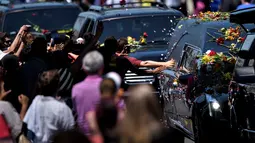 Beberapa orang berusaha menyentuh mobil jenazah Muhammad Ali menuju pemakaman Cave Hill di Louisville, Kentucky, AS, (10/6/2016). Ribuan orang memberi penghormatan terakhir di sepanjang jalan menuju pemakaman. (AFP/Brendan Smialowski)