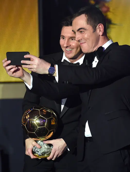 Pemain Barcelona, Lionel Messi berselfie bersama aktor James Nesbitt setelah memenangkan pemain terbaik dunia FIFA Ballon d'Or 2015 di Kongresshaus, Zurich, Senin ( 11/1). Ini adalah kelima kalinya Messi meraih Ballon d'Or. (AFP PHOTO/FABRICE COFFRINI)