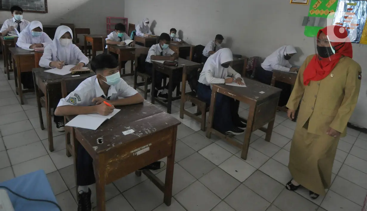 Guru mengajar para murid saat pelaksanaan uji coba pendidikan tatap muka (PTM) di SMPN 15, Kota Bogor, Jawa Barat, Senin (31/5/2021). Pemerintah Kota Bogor menggelar uji coba PTM di 37 sekolah hari ini dengan protokol kesehatan yang ketat. (merdeka.com/Arie Basuki)