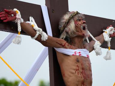 Wilfredo Salvador meringis setelah dia dipaku pada kayu salib saat memperagakan kembali penderitaan Yesus Kristus sebagai bagian dari ritual Jumat Agung di Desa San Pedro, Cutud, Provinsi Pampanga, Filipina, Jumat (7/4/2023). Penyaliban di kehidupan nyata, tradisi Jumat Agung berdarah yang ditolak oleh gereja Katolik, dilanjutkan di desa pertanian ini setelah jeda tiga tahun karena pandemi virus corona COVID-19. (AP Photo/Aaron Favila)