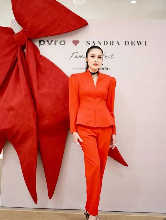 Sandra Dewi mengenakan atasan plum merah lengan panjang yang dipadukan celana warna serasi. Kalung hitam cocker melengkapi penampilan. [@sandradewi88]