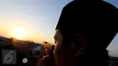 Seorang anggota tim Rukyatul Hilal meneropong posisi hilal di atas Mesjid Al Musriyiin, Jakarta, Kamis (16/7/2015). Berdasarkan data astronomis ketinggian hilal saat matahari terbenam sekitar tiga derajat. (Liputan6.com/Helmi Afandi)
