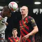 Bek Fulham, Issa Diop menjauhkan bola dari jangkauan penyerang Manchester City, Erling Haaland dalam lanjutan Premier League 2022/2023, Minggu (30/4/2023) malam. (AFP/Adrian Dennis)