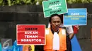Seorang anggota Indonesia Corruption Watch (ICW) menunjukan poster saat menggelar aksinya di Car Free Day dikawasan Bunderan HI, Jakarta, Minggu (12/2). (Liputan6.com/Faizal Fanani)