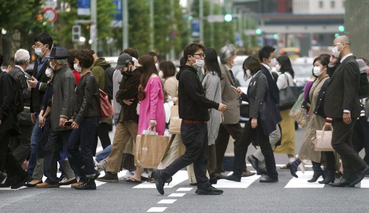 Orang-orang yang mengenakan masker untuk membantu mengekang penyebaran virus corona COVID-19 berjalan melintasi penyeberangan pejalan kaki di Tokyo, Jepang, Rabu (28/10/2020). Tokyo mengonfirmasi lebih dari 170 kasus virus corona COVID-19 baru pada 28 Oktober 2020. (AP Photo/Eugene Hoshiko)