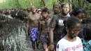 Warga Bali berjalan bersama dengan badan penuh lumpur saat mengikuti mandi lumpur tradisional atau yang dikenal sebagai Mebuug-buugan di desa Kedonganan, Bali (18/3). (AFP/Sony Tumbelaka)