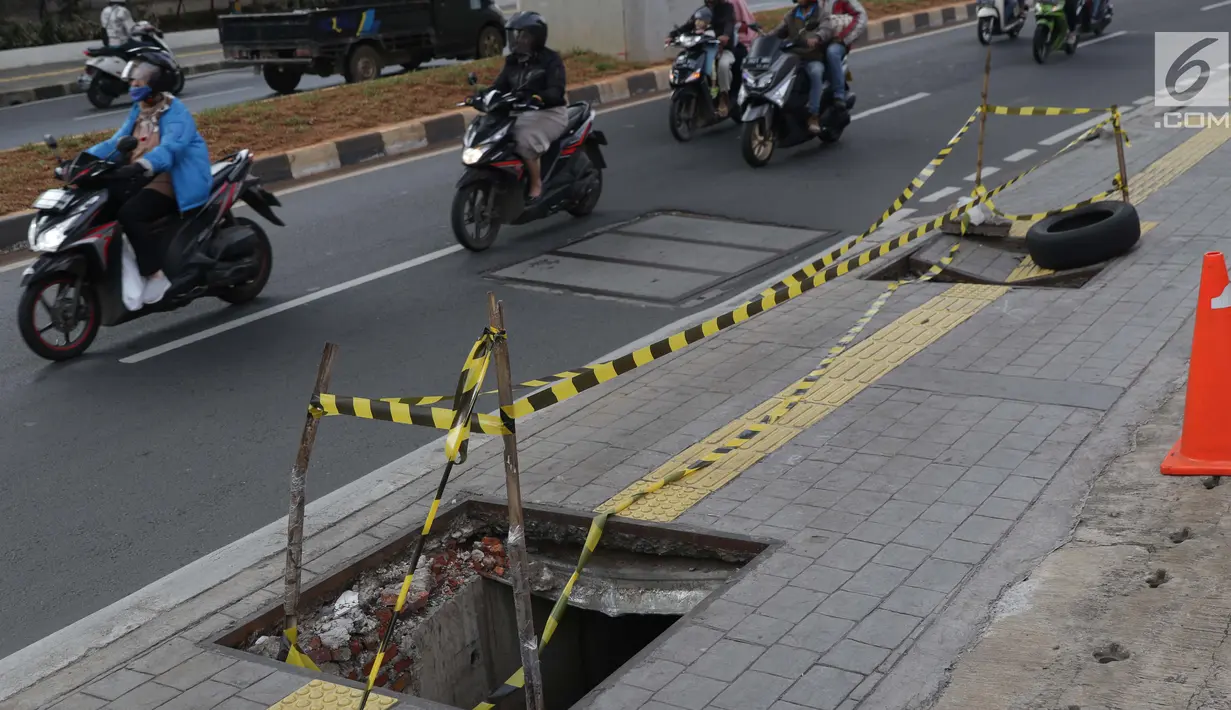 Pengendara melintas di dekat penutup trotoar yang rusak di kawasan Jalan RS Fatmawati, Jakarta, Selasa (14/7/2019). Dua buah penutup trotoar di Jalan RS Fatmawati rusak parah, kondisi ini mengganggu kenyamanan dan membahayakan pejalan kaki, terutama pada malam hari. (Liputan6.com/Helmi Fithriansyah)