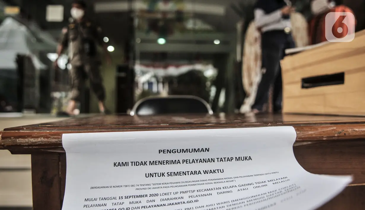 Petugas berada di dekat selebaran info ditiadakannya pelayanan tatap muka di depan Kantor Kecamatan Kelapa Gading, Jakarta, Senin (21/9/2020). Kantor Kecamatan Kelapa Gading ditutup hingga Rabu (23/9), pasca meninggalnya Camat Kelapa Gading, M Harmawan akibat COVID-19. (merdeka.com/Iqbal Nugroho)
