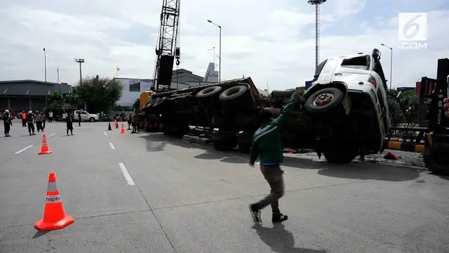 Diduga akibat kelebihan muatan truk yang bermuatan paku bumi terbalik di jalan kawasan pelabuhan Tanjung Priok.