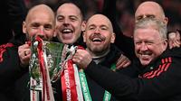 Pelatih Manchester United, Erik Ten Hag bersama sejumlah asisten pelatih memamerkan trofi Carabao Cup 2023 setelah mengalahkan Newcastle United di Wembley Stadium, Minggu (26/2/2023) waktu setempat. Ini merupakan trofi pertama yang dipersembahkan pelatih asal Belanda tersebut. (AFP/Glyn Kirk)