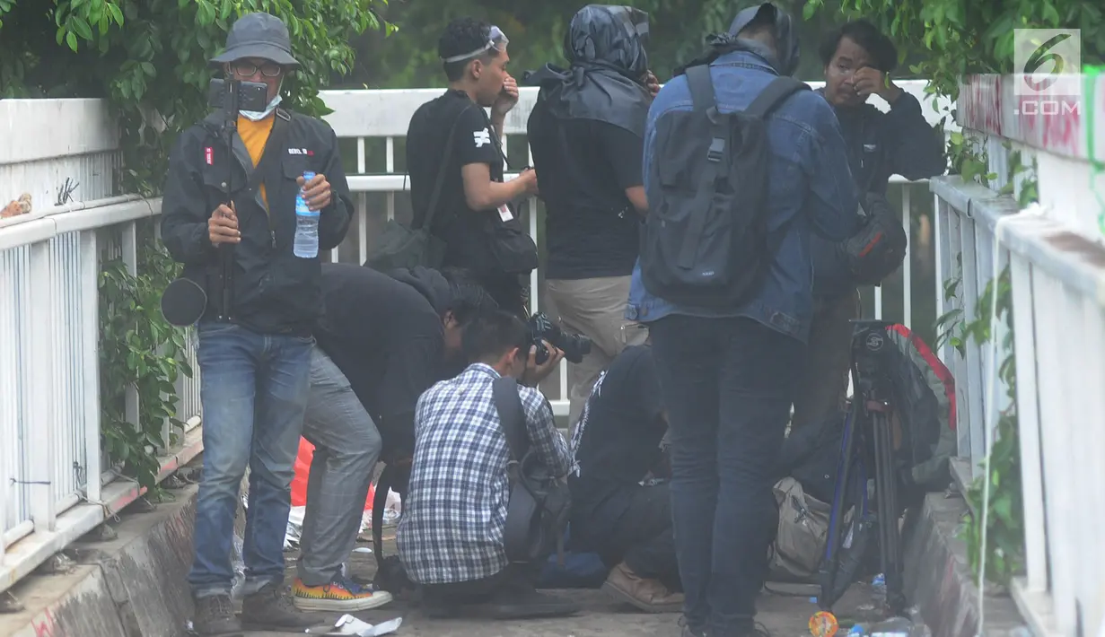 Jurnalis melindungi dirinya saat meliput demontrasi yang memanas di depan gedung Dewan Perwakilan Rakyat (DPR), Senayan, Jakarta, Selasa (24/9/2019). Polisi menembakkan gas air mata dan meriam air untuk membubarkan massa aksi yang menolak RKUHP dan RUU kontroversial lain. (merdeka.com/Arie Basuki)