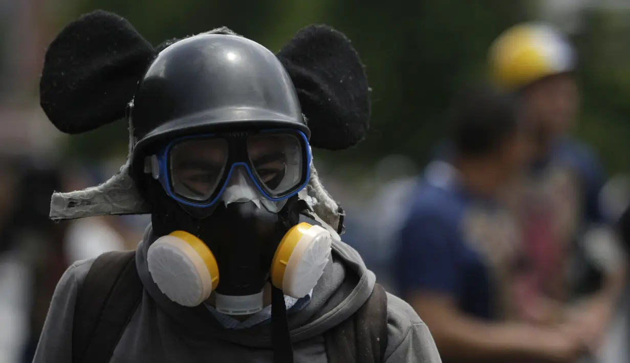 Demonstran anti-pemerintah di Venezuela mengenakan masker saat menggelar aksi di Caracas, Venezuela, Sabtu (26/5). Demonstran menuntut Maduro untuk turun dari jabatan presiden. (AP Photo)  