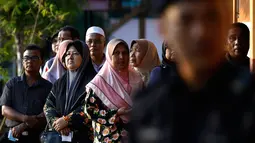 Seorang polisi berjaga saat warga Malaysia mengantre untuk menggunakan hak pilih mereka di tempat pemungutan suara (TPS) di Alor Setar, ibu kota negeri Kedah, Rabu (9/5). Pemilihan umum Malaysia ini untuk menentukan Perdana Menteri. (AP Photo/Andy Wong)