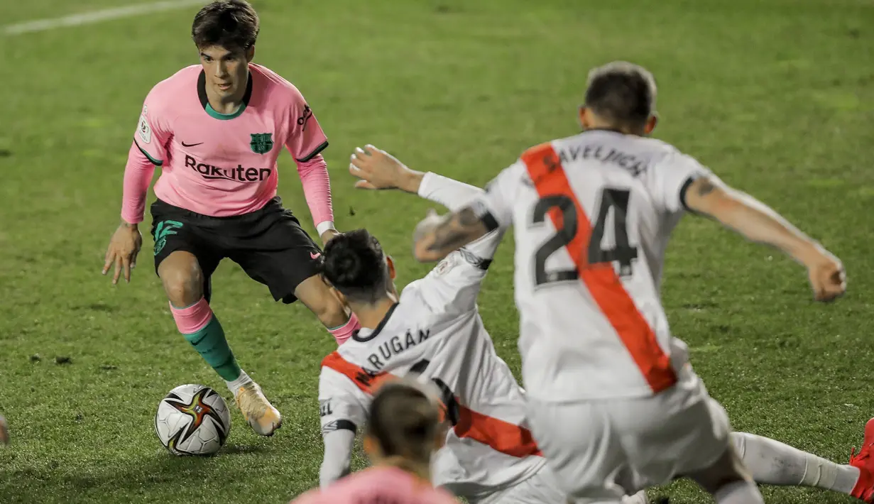 Pemain Barcelona, Riqui Puig (kiri) mengecoh pemain Rayo Vallecano pada laga babak 16 Besar Copa del Rey di Vallecas stadium, Madrid, Kamis (28/1/2021). (Foto: AP/Manu Fernandez)