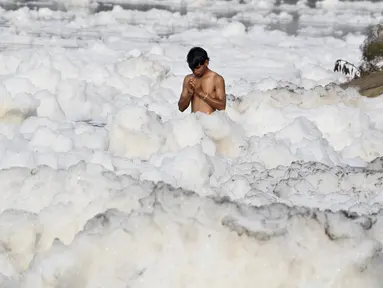 Seorang pria berdoa di Sungai Yamuna yang tercemar di New Delhi, Sabtu (8/7). Umat Hindu India mensucikan dua sungai di India yaitu Sungai Ganggga dan Yamuna. (DOMINIQUE FAGET / AFP)