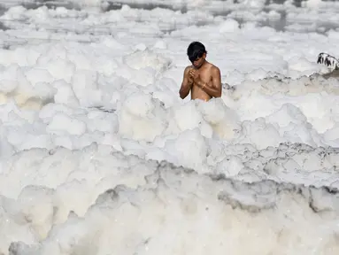 Seorang pria berdoa di Sungai Yamuna yang tercemar di New Delhi, Sabtu (8/7). Umat Hindu India mensucikan dua sungai di India yaitu Sungai Ganggga dan Yamuna. (DOMINIQUE FAGET / AFP)
