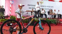 Seorang bocah SD menerima hadiah sepeda usai menjawab pertanyaan Presiden Jokowi dalam acara penyerahan KIP dan PKH di SMA Negeri 1 Palembang, Sumatra Selatan (22/1). (Liputan6.com/Pool/Biro Setpres)