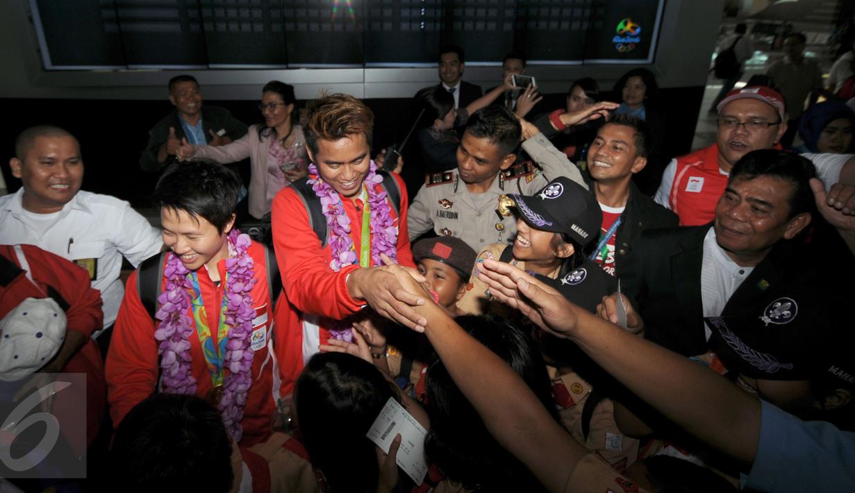 Sejumlah orang berusaha bersalaman dengan Lilyana NatsirdanTontowi Ahmad usai tiba di Bandara Soekarno Hatta, Banten, Selasa (23/8/2016). Tontowi Ahmad/Lilyana Natsir berhasil meraih emas olimpiade Rio 2016 di Brasil. (Liputan6.com/HelmiFithriansyah)
