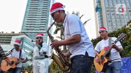 Musisi mengelar pertunjukan musik bernuansa Natal di jalur Pedestrian Bundaran HI, Jakarta Pusat, Selasa (20/12/2022). Pergelaran musik bernuansa Natal tersebut sebagai bentuk pertunjukan untuk menghibur warga yang melintas di Kawasan itu. (Liputan6.com/Angga Yuniar)