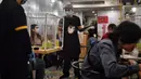 Pramusaji dengan pelindung wajah melayani pelanggan di restoran hotpot Penguin Eat Shabu di Bangkok, 5 Mei 2020. Restoran yang memasang pembatas plastik itu kembali dibuka setelah Thailand memperlonggar lockdown dengan mengizinkan tempat makan menerapkan social distancing. (Lillian SUWANRUMPHA/AFP)