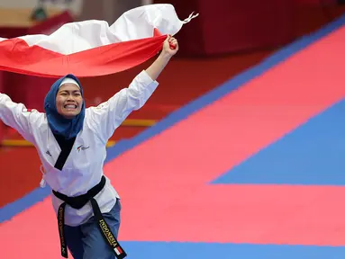 Atlet taekwondo, Defia Rosmaniar, melakukan selebrasi usai berhasil meriah medali emas pertama untuk Indoensia di Asian Games 2018 di JCC, Jakarta, Minggu (19/8/2018). (Bola.com/Peksi Cahyo)