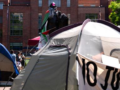 Para aktivis dan mahasiswa berunjuk rasa di dekat perkemahan di University Yard di Universitas George Washington pada 28 April 2024 di Washington, DC. (Kent Nishimura/Getty Images North America/Getty Images via AFP)