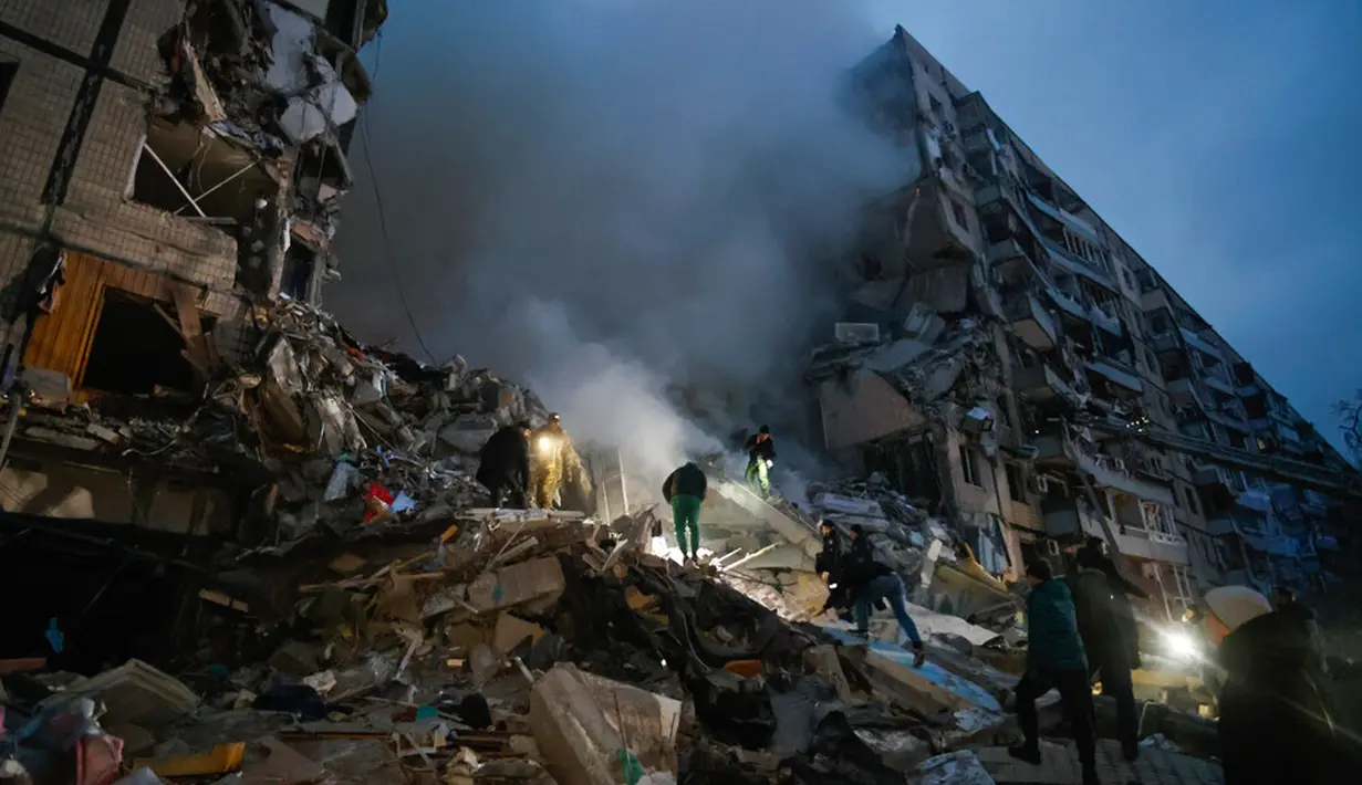 Warga membersihkan puing-puing setelah rudal Rusia menghantam apartemen di Kota Dnipro, Ukraina, 14 Januari 2023. Rusia meluncurkan gelombang serangan besar untuk memukul infrastruktur energi di Ukraina termasuk sebuah gedung apartemen sembilan lantai di Kota Dnipro yang menyebabkan 12 orang tewas. (AP Photo/Roman Chop)