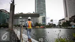 Pekerja melintas di kolam Bundaran HI, Jakarta, Rabu (23/3). Pemasangan penyanggah bertujuan untuk menahan Tugu Selamat Datang di Bundaran HI dari getaran saat Bor Antareja proyek Mass Rapid Transit (MRT) melintas dibawahnya. (Liputan6.com/Faizal Fanani)