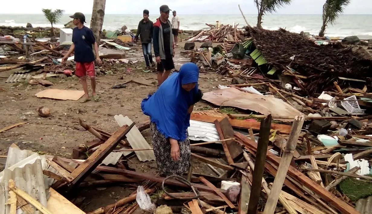 Warga memeriksa kerusakan rumah mereka setelah tsunami menerjang Pantai Carita, di perairan Banten, Minggu (23/12). Data sementara jumlah korban dari bencana tsunami di Selat Sunda tercatat 584 orang luka-luka dan 2 orang dinyatakan hilang. (SEMI / AFP)