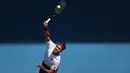 Petenis Swiss, Roger Federer, mengembalikan bola saat melawan petenis AS, Tennys Sandgren, pada perempat final Australia Open 2020 di Melbourne, Selasa (28/1). Federer menang 6-3, 2-6, 2-6, 7-6 (10-8), 6-3 atas Sandgren. (AFP/David Gray)
