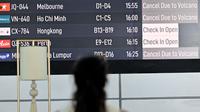 Seorang penumpang melihat papan elektronik yang menampilkan pembatalan penerbangan setelah gunung berapi Lewotobi Laki-Laki meletus di Bandara Internasional Ngurah Rai di Tuban dekat Denpasar, Bali, pada 18 Juni 2025. (SONNY TUMBELAKA/AFP)