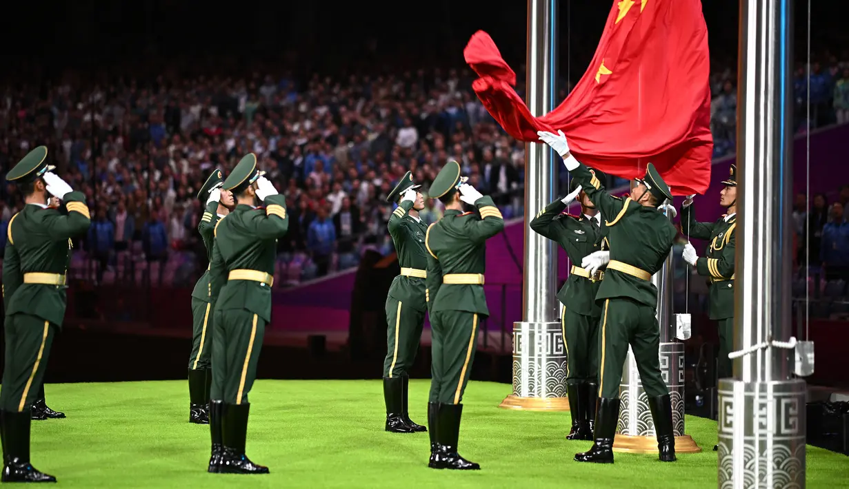 Sejumlah petugas memberikan penghormatan saat penurunan bendera ketika upacara penutupan Asian Games 2022 yang berlangsung di Hangzhou Olympic Sports Centre Stadium, Hangzhou, China pada Minggu (08/10/2023). (AFP/Philip Fong)