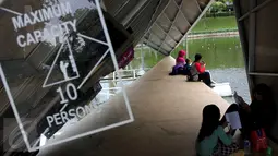 Sejumlah warga membaca buku di perpustakaan apung Taman Ayodya, Jakarta, Senin (4/1/2015). Perpustakaan apung Ayodya Script merupakan sebuah karya instalasi berupa micro library terbuat kontekstual terapung di atas kolam. (Liputan6.com/Johan Tallo)