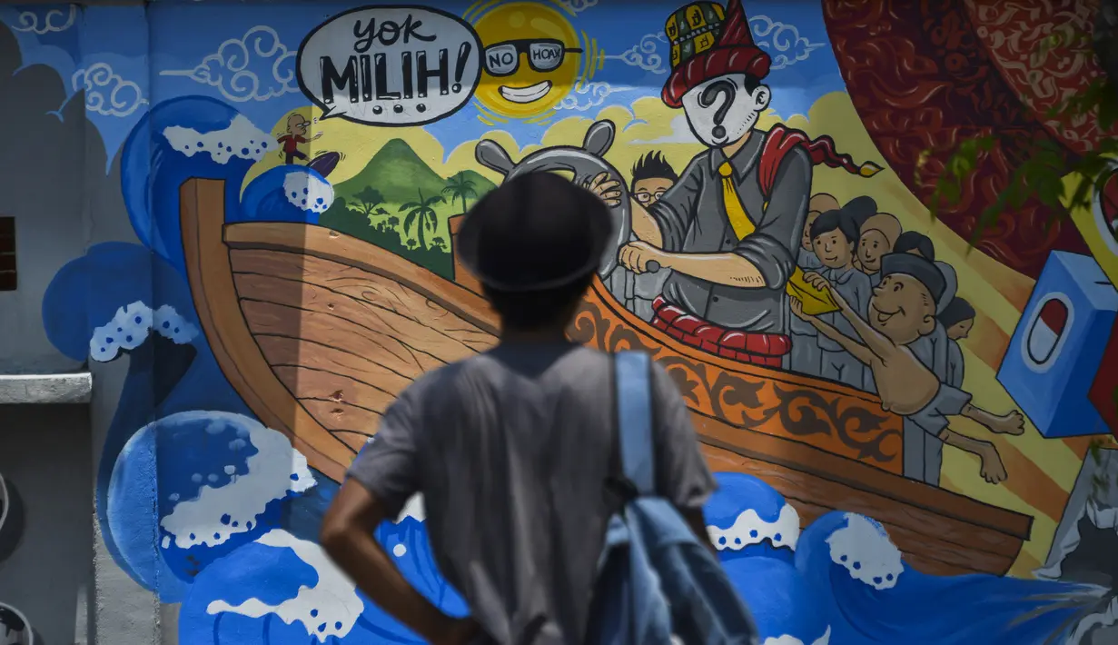 Seorang pria berdiri di depan sebuah mural kampanye pemilu 2019 di Banda Aceh, provinsi Aceh (17/3). Indonesia akan mengadakan pemilihan presiden dan parlemen secara serentak pada 17 April. (AFP Photo/Chaideer Mahyuddin)