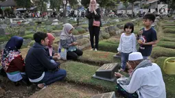 Sebuah keluarga menggelar doa 'Talkin' yang dipimpin oleh Muhammad Hoir di TPU Kemiri, Rawamangun, Jakarta, Selasa (15/5). Setiap tahunnya, Hoir datang ke TPU Kemiri seminggu sebelum puasa dan kembali lagi setelah Lebaran. (Merdeka.com/Iqbal S Nugroho)
