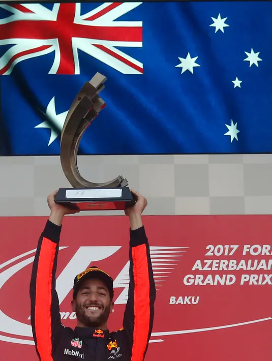 Pembalap Red Bull, Daniel Ricciardo mengangkat trofi usai memenangkan balapan GP Azerbaijan di Sirkuit Baku City, Minggu (25/6). Ricciardo yang memulai dari posisi 10 mencatatkan waktu 1 jam 41 menit untuk melahap 51 putaran. (AP Photo/Darko Bandic)